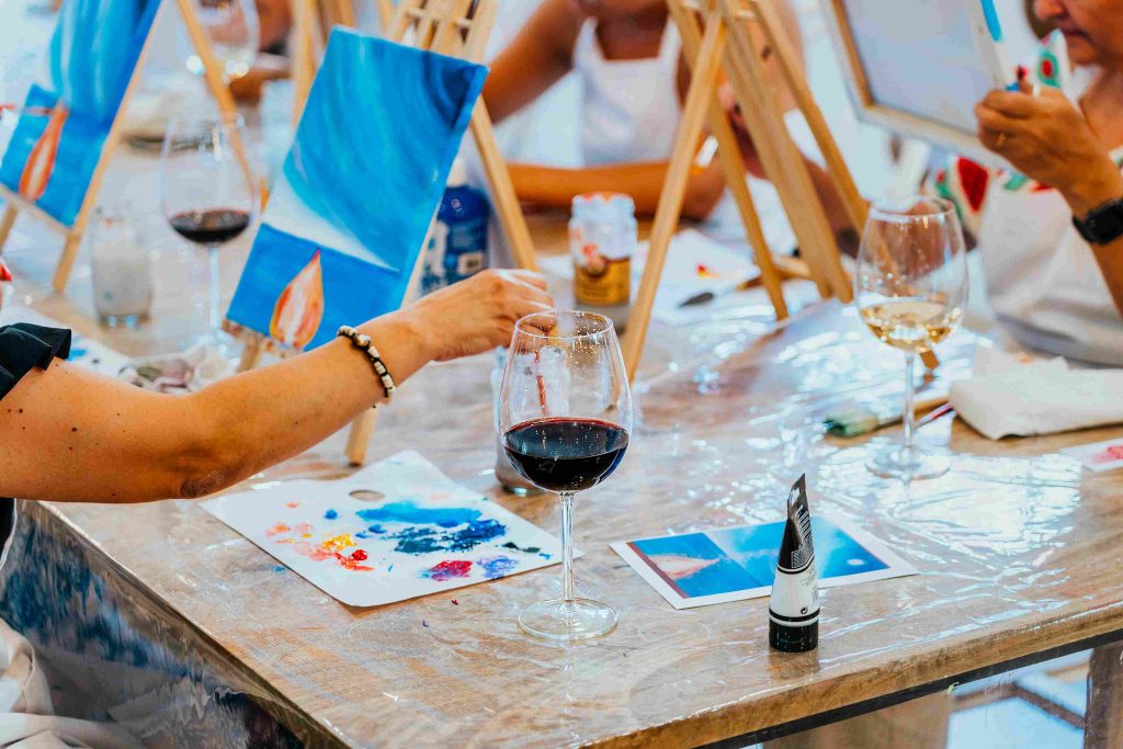 Painting and wine-tasting women immersed in arts